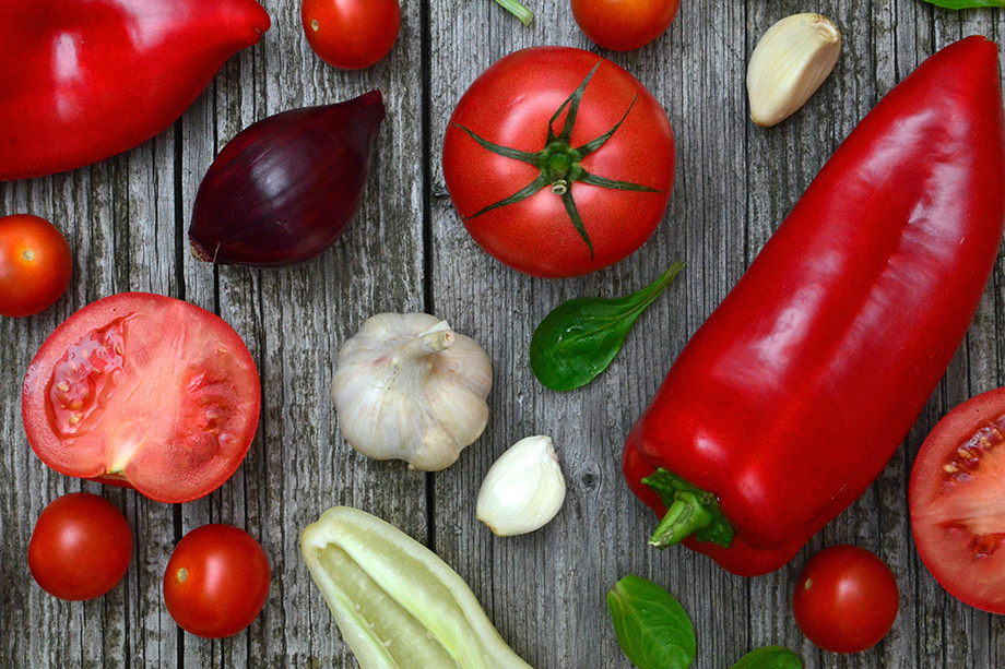 Verschiedene Gemüsesorten wie Paprika und Paradeiser liegen auf einem Holztisch