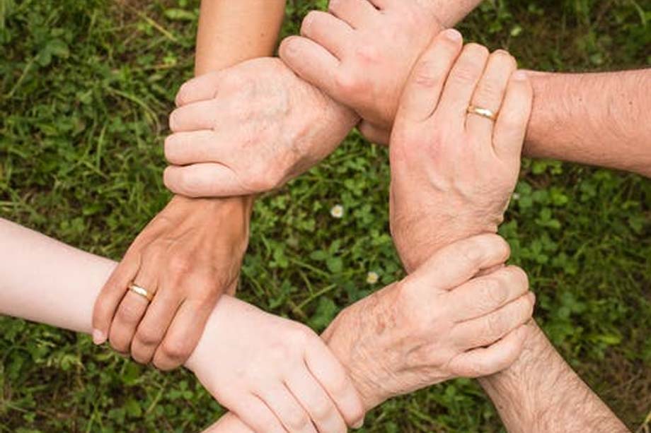 Sechs Hände fassen sich im Kreis und symbolisieren so ein Miteinander