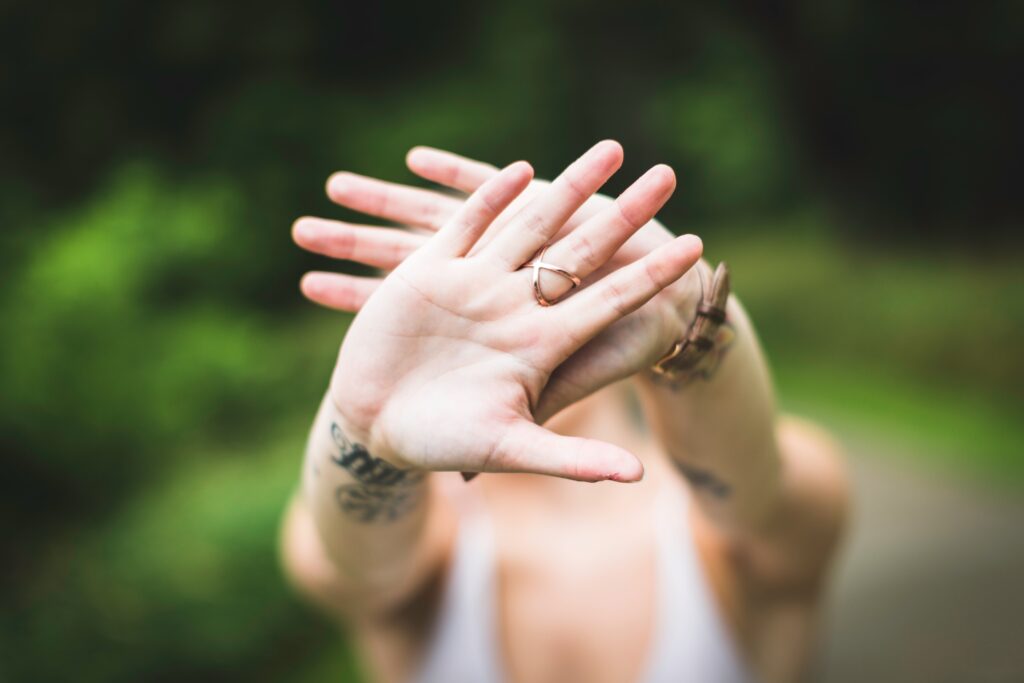 Eine Frau streckt ihre übereinandergelegten Hände zur Abwehr in die Kamera