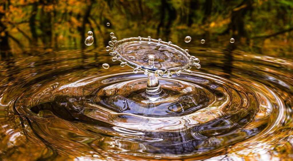 Ein hochspringender Wassertropfen versetzt einen See in Wellenbewegung