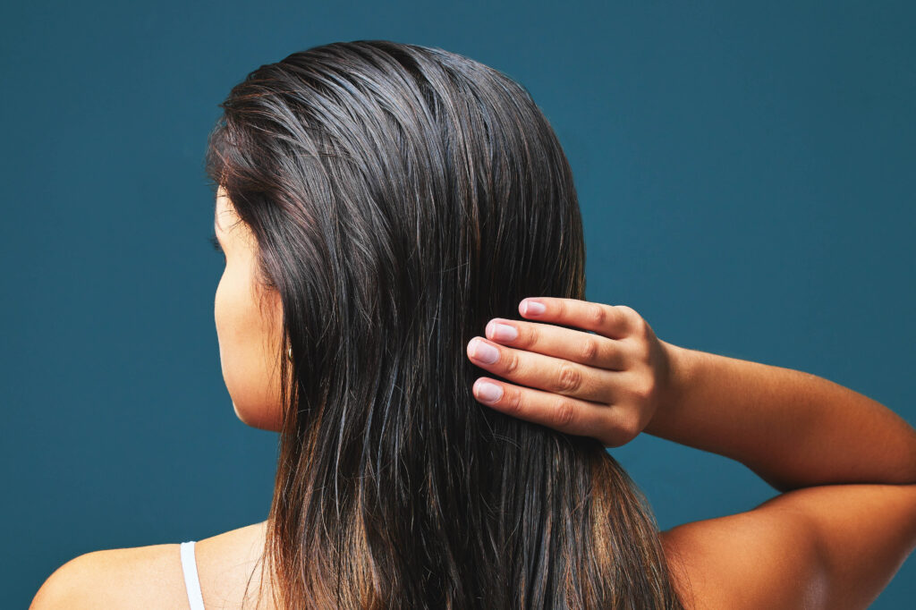 Eine Frau greift mit den Fingern in ihr sichtbar fettiges Haar