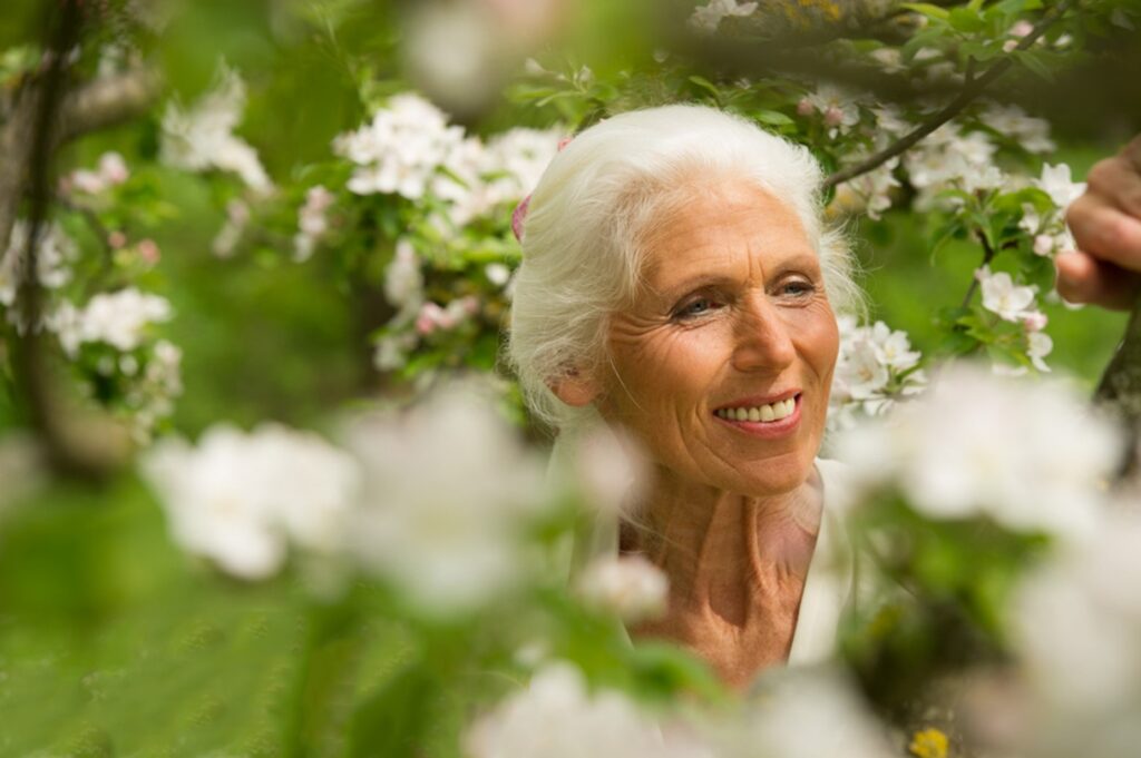 Ältere Damen mit weißem Haar inmitten eines blühenden Baumes