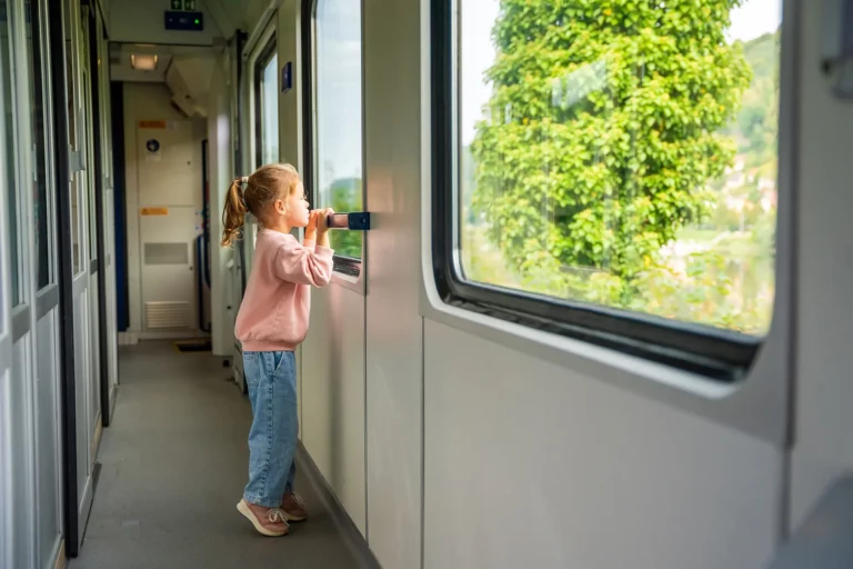Kleines Mädchen steht im Zug und sieht aus dem Fenster