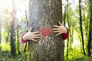 Ein von einem Baum verdecktes Mädchen umarmt diesen von hinten