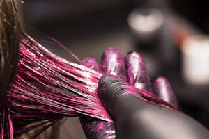 Behandschuhte Hand hält eine pinke Haarsträhne