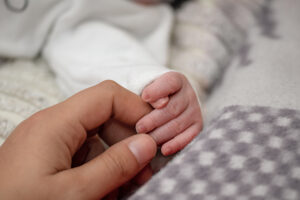 Ein Baby berührt mit seinen Fingern die Hand seiner Mutter