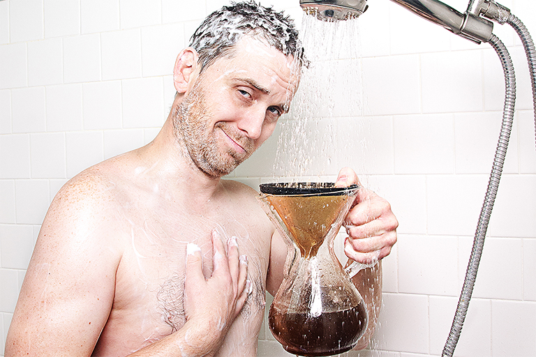 Mann steht mit einem Kaffeefilter unter der laufenden Dusche