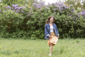 Eine junge Frau hüpft vor Freude auf einer Blumenwiese