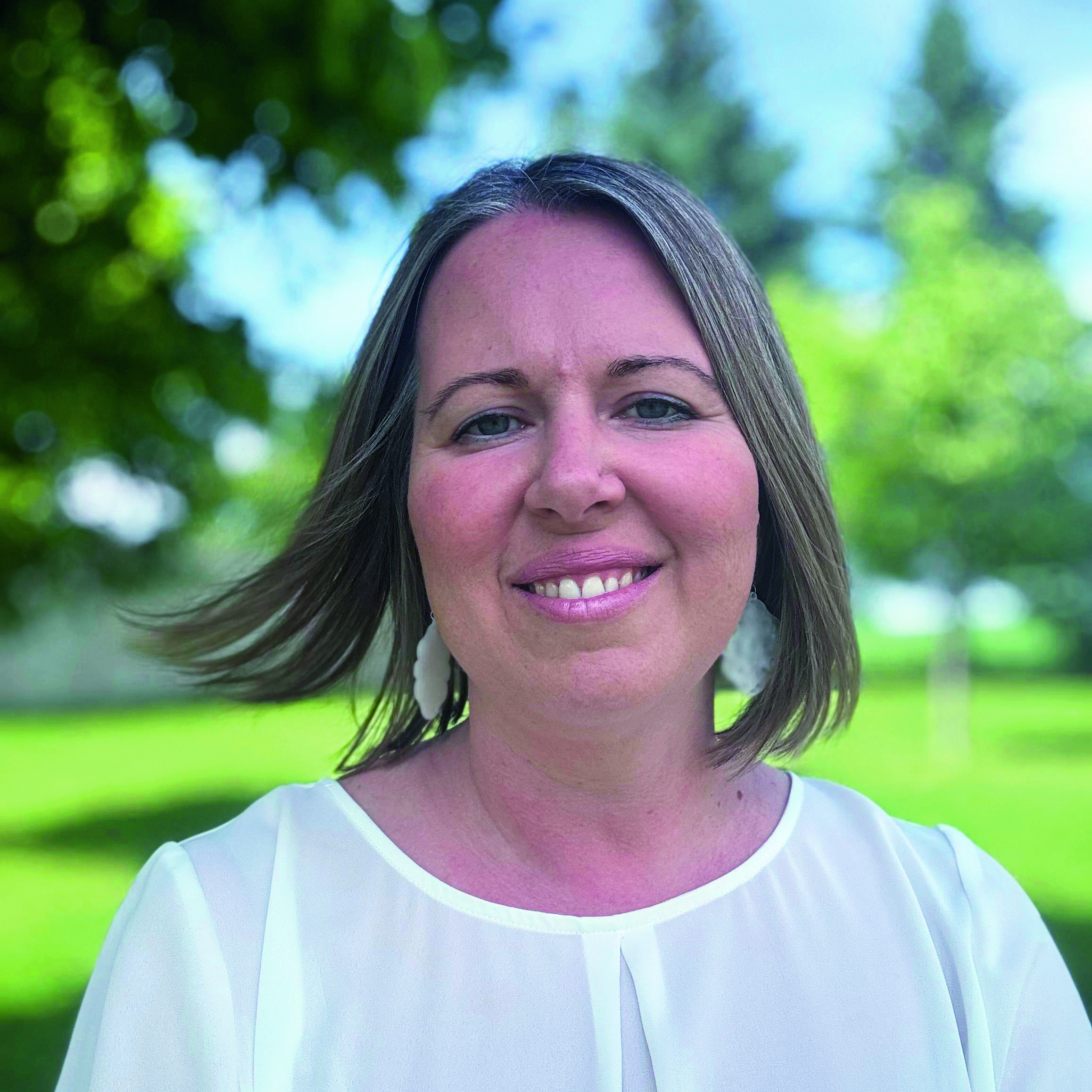 Eine Frau mittleren Alters und mit kurzen Haaren lächelt in die Kamera