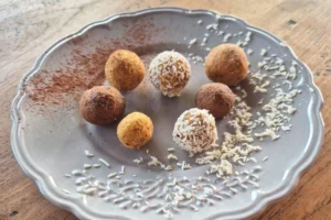 Gesunde Kraft-Kugeln für Kinder mit Karotte, Mandel und Datteln, in Kokosraspeln und Kakaopulver gewälzt.
